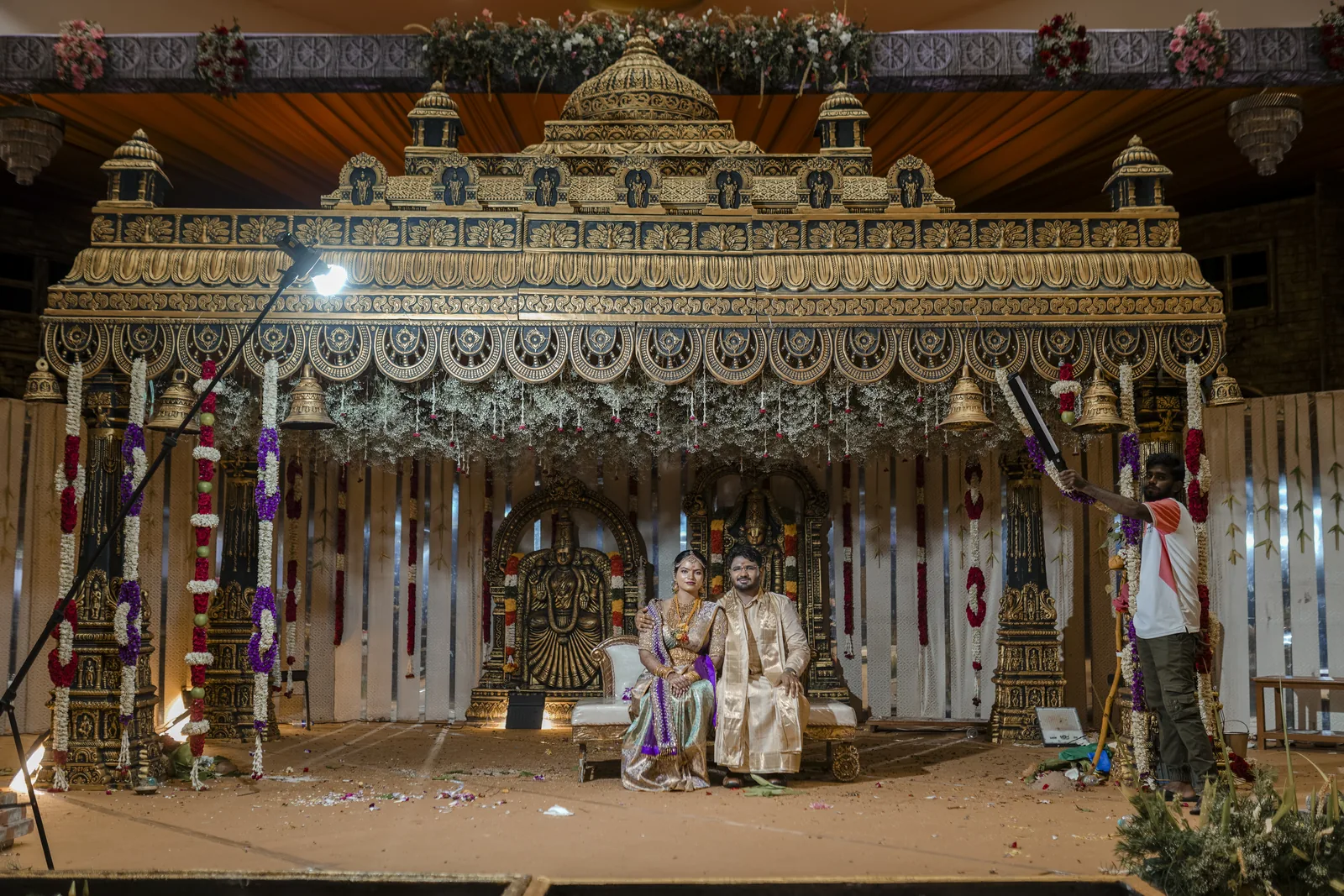 A carved wooden wedding mandap with floral pillars
