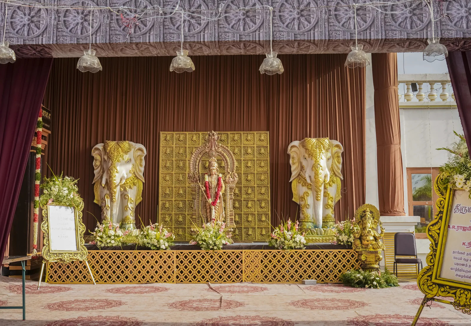 A wedding stage with a gold shrine flanked by two ceremonial elephants