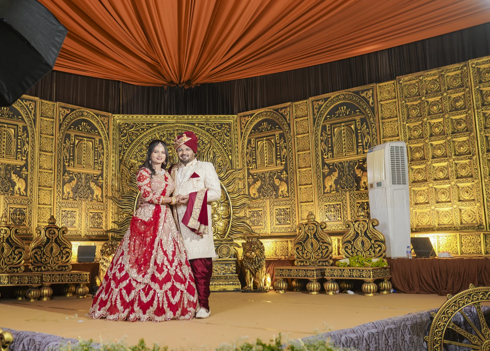 A gold reception backdrop under a draped ceiling